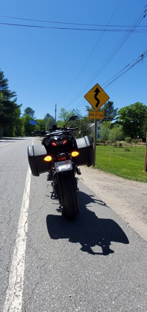 Motorcycle pulled to the side of the road, a big blue sky above 